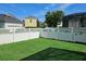 Backyard featuring a lush, green lawn, white vinyl fence, and partial view of the property at 1414 Stickley Ave, Kissimmee, FL 34747