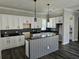 Open-concept kitchen featuring a gray kitchen island, sleek black countertops, and white cabinets at 1414 Stickley Ave, Kissimmee, FL 34747