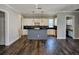 Open-concept kitchen featuring a gray kitchen island, sleek black countertops, and white cabinets at 1414 Stickley Ave, Kissimmee, FL 34747