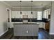 Open-concept kitchen featuring a gray kitchen island, sleek black countertops, and white cabinets at 1414 Stickley Ave, Kissimmee, FL 34747