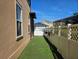 A glimpse of the side yard, with artificial grass, a white fence, and the side of the home at 1414 Stickley Ave, Kissimmee, FL 34747