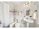 White bathroom with black and white tiled floors, a shower and tub, and a pedestal sink at 1420 Palmer Ave, Winter Park, FL 32789