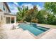 A beautiful pool with waterfall feature, travertine pavers, and lush landscaping, perfect for outdoor relaxation at 1420 Palmer Ave, Winter Park, FL 32789