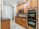 Close up of kitchen featuring stainless steel double oven and microwave, black countertop, and ample wood cabinetry at 1429 Arbitus Cir, Oviedo, FL 32765