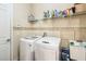 Functional laundry room equipped with a washer, dryer, storage shelves, and ample space for laundry tasks at 1429 Arbitus Cir, Oviedo, FL 32765
