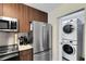 Modern kitchen with stainless steel appliances, including a refrigerator, microwave, and a stacked washer/dryer at 14501 Grove Resort Ave # 2451, Winter Garden, FL 34787