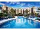 Stunning pool area with lounge chairs and umbrellas surrounded by tropical landscaping and the building's reflection at 14501 Grove Resort Ave # 2451, Winter Garden, FL 34787