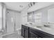 Bright bathroom features a double vanity with black cabinets, quartz countertops, and a tiled shower with glass doors at 15096 Chapter Way, Winter Garden, FL 34787