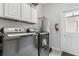 The laundry room features white cabinets above the washer and dryer and a hot water tank in the corner at 15096 Chapter Way, Winter Garden, FL 34787