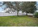 Picturesque backyard showcasing a lush green lawn with mature trees and a pristine white fence at 2306 Valhalla Dr, Tavares, FL 32778