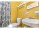 A yellow bathroom features a toilet, a sink, and a patterned shower curtain at 2518 Fort Lane Rd, Geneva, FL 32732