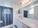 Bright bathroom featuring a shower with a blue curtain, arched window, and a vanity with bright lighting at 2729 N Poinciana Blvd # 125, Kissimmee, FL 34746