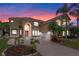 Grand two-story home featuring a brick driveway, arched entry, and lush tropical landscaping at twilight at 2828 Northampton Ave, Orlando, FL 32828