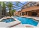 The screened outdoor area offers a beautiful swimming pool with a hot tub surrounded by mature trees at 2828 Northampton Ave, Orlando, FL 32828