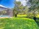 Spacious backyard featuring a fenced yard, lush green lawn, mature trees and screened-in pool area at 3216 Rolling Hills Ln, Apopka, FL 32712
