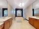 Bathroom featuring dual vanities, mirrors, tiled floors, and a large tub with shower at 3216 Rolling Hills Ln, Apopka, FL 32712