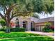 Inviting single-story home with lush green lawn, mature shade trees, and a classic brick driveway leading to a two-car garage at 3216 Rolling Hills Ln, Apopka, FL 32712
