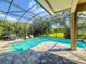 Inviting screened-in pool area with stone pavers, outdoor seating, and a view of the lush backyard at 3216 Rolling Hills Ln, Apopka, FL 32712