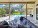 Captivating view from covered patio with relaxing lounge furniture, overlooking a sparkling pool, and lush green backyard at 3216 Rolling Hills Ln, Apopka, FL 32712