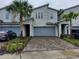 Attractive townhome featuring a two-car garage, modern design, palm trees, and brick paver driveway at 3316 Bellissimo Ave, Kissimmee, FL 34746
