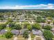 Aerial view showcasing a neighborhood with mature trees, well-maintained homes, and clear blue skies at 3443 Arnel Dr, Winter Park, FL 32792