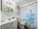 Bright bathroom with white fixtures, a coral-themed shower curtain, and a round mirror at 3443 Arnel Dr, Winter Park, FL 32792