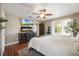 Bright bedroom features a ceiling fan, a king bed, wood floors, and television with decorative fireplace beneath at 5113 Mystic Point Ct, Orlando, FL 32812