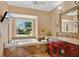 Primary bathroom featuring a garden tub, wooden vanity, and granite countertop at 603 S Sweetwater Blvd, Longwood, FL 32779