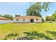 Expansive backyard showcasing the home's exterior with a green lawn and mature trees at 620 Unabelle Ave, Holly Hill, FL 32117