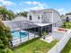 Back exterior view of a gray two-story home featuring a screened-in pool area and lush green lawn, with landscaping at 754 Birgham Pl, Lake Mary, FL 32746