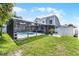 Backyard view of a gray two-story home featuring a screened-in pool area and lush green lawn, with landscaping at 754 Birgham Pl, Lake Mary, FL 32746