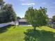 Expansive backyard featuring a well-maintained lawn, mature trees, a screened patio, and room for outdoor activities at 7911 Murcott Cir, Orlando, FL 32835