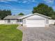 Charming single-story home with a manicured lawn, gray brick driveway, and an attached two-car garage at 7911 Murcott Cir, Orlando, FL 32835
