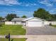 Charming single-story home with a manicured lawn, brick driveway, and a two-car garage at 7911 Murcott Cir, Orlando, FL 32835