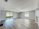 Open living room with light wood floors, ceiling fan, and sliding glass doors leading to outdoor space at 7911 Murcott Cir, Orlando, FL 32835