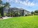 Backyard features a screened-in patio with lush greenery and a meticulously manicured lawn at 8080 Peaceful Cir, Sanford, FL 32771