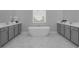 Elegant bathroom featuring a sleek, free-standing tub, marble floors, and dual vanities with gray cabinets at 8080 Peaceful Cir, Sanford, FL 32771