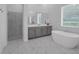 Bright bathroom with a modern shower stall and a freestanding tub, complemented by gray cabinets and marble-look floors at 8080 Peaceful Cir, Sanford, FL 32771