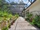 Screened-in patio showcases potted plants, a brick path, and lush greenery for a relaxing outdoor retreat at 8080 Peaceful Cir, Sanford, FL 32771