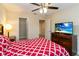 Comfortable bedroom featuring a TV, ceiling fan and a door to a walk-in closet at 8219 Roseville Blvd, Davenport, FL 33896