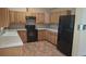 Well-lit kitchen with light wood cabinets, tile countertops, and modern black appliances at 900 Red Fox Rd, Altamonte Springs, FL 32714