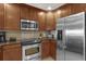 Kitchen with stainless steel appliances, tile backsplash, wooden cabinets, and a modern microwave at 1100 Sunset View Cir # 204, Reunion, FL 34747