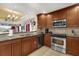 Kitchen with stainless appliances, tile floors, and wooden cabinets, with a view to the living room at 1100 Sunset View Cir # 204, Reunion, FL 34747