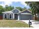 Charming gray home featuring arched windows, a two-car garage, and manicured landscaping at 1322 Reagans Reserve Blvd, Apopka, FL 32712