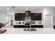 A modern kitchen features dark cabinets, stainless steel appliances, a white countertop island with a sink at 14357 Hidden Ct, Clermont, FL 34711