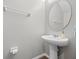Clean powder room featuring a pedestal sink, oval mirror, and neutral walls with wood-look flooring at 150 Mitchell Creek Way, Oviedo, FL 32765