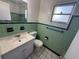 Modest bathroom featuring green tiling, white fixtures, and floral accents above the tiling at 1506 Carmen Ave, Daytona Beach, FL 32117