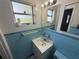 Bathroom featuring a blue tiled sink area, toilet and a frosted window for natural light at 1506 Carmen Ave, Daytona Beach, FL 32117