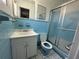 Cozy bathroom with blue tiling, toilet, sink, vanity and glass shower door at 1506 Carmen Ave, Daytona Beach, FL 32117