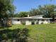 Rear exterior view of a single-story home with a spacious backyard and mature trees at 1526 Cordova Ave, Holly Hill, FL 32117